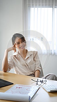 Happy female accountant sitting at her workplace and laughing.