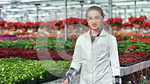 Happy female agricultural engineer in uniform posing at modern greenhouse medium shot
