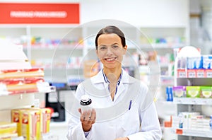 Happy female apothecary with drug at pharmacy