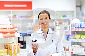 Happy female apothecary with drug at pharmacy photo
