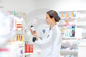 Happy female apothecary with drug at pharmacy