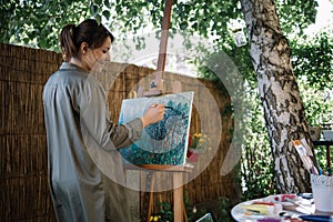 Happy female artist painting in nature using paint brush