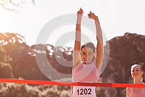 Happy female athlete with arms raised crossing finish line photo
