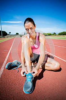 Happy female athlete tying her running shoes