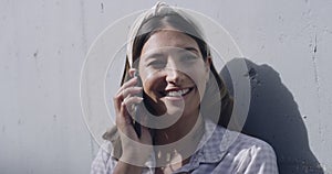 Happy female catching up and chatting with a loved one over the phone in the city. Young woman talking on a call with a