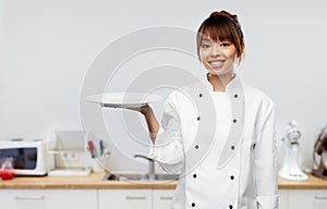 happy female chef holding empty plate on kitchen
