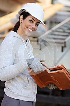 happy female construction worker on site laying slate tiles