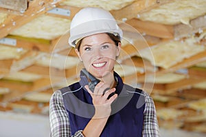 Happy female construction worker using talkie walkie