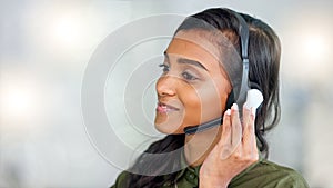 Happy female customer service agent smiling while working in a call centre and talking to a client with a headset. A