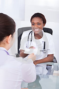 Happy female dentist giving prescription to patient