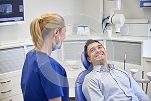 Happy female dentist with man patient at clinic