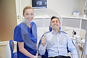 Happy female dentist with man patient at clinic