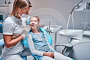 Happy female dentist with patient girl at clinic