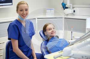 Happy female dentist with patient girl at clinic