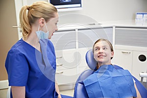 Happy female dentist with patient girl at clinic