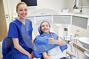 Happy female dentist with patient girl at clinic