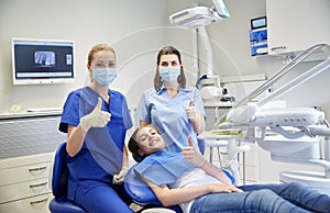 Happy female dentist with patient girl at clinic