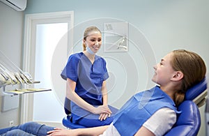 Happy female dentist with patient girl at clinic