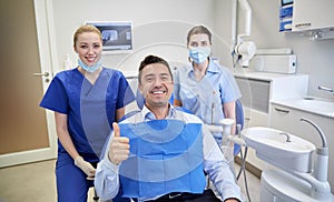 Happy female dentists with man patient at clinic