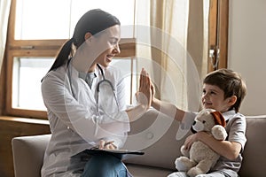 Happy female doctor give high five to small boy patient