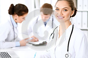 Happy female doctor with medical staff while sitting at the table
