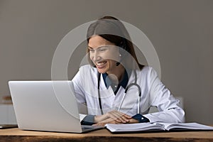 Happy female doctor, physician in headphones giving online consultation