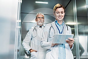 happy female doctor using digital tablet while her male colleague standing behind