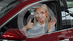 Happy female driver showing her car keys and thumbs up