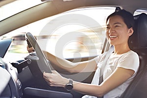 Happy female driver steering car with safety belt