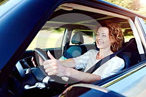 Happy female driver steering car with safety belt