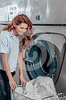 happy female dry cleaning worker taking clothes out of