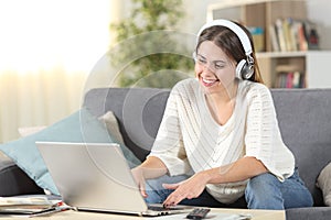 Happy female e-learning using headphones and laptop