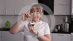 Happy female eating cherry from cake in kitchen