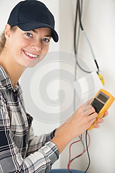 Happy female electrician testing wall socket