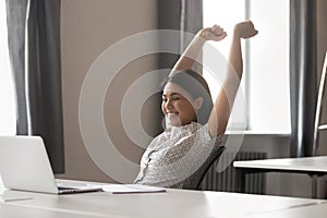 Happy female employee stretch in chair finishing work