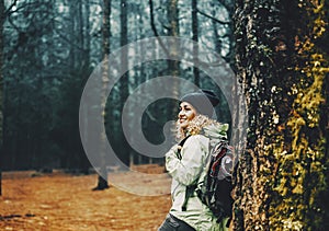 Happy female excursionist enjoy nature background and forest around smiling and resting against a tree. Travel backpacker woman in