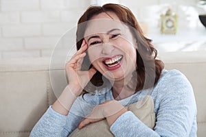 Happy female face. Attractive and beautiful middle aged woman sitting on sofa .