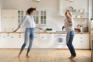 Happy female family dancing together in modern kitchen.