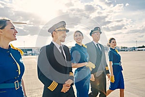 Happy female flight attendants and airline pilots going ahead