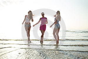 Happy female friends dancing on beach