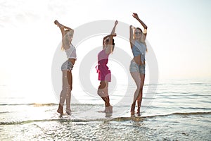 Happy female friends dancing on beach