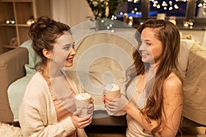 Happy female friends drinking cacao at home