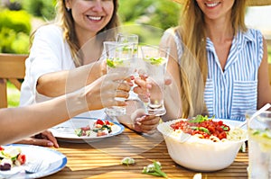 Happy female friends with glasses of lemonade at dining table in