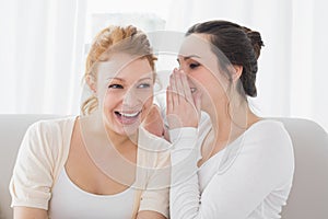 Happy female friends gossiping in living room