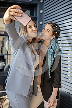 Happy female friends posing taking selfie photographing together use smartphone enjoying friendship