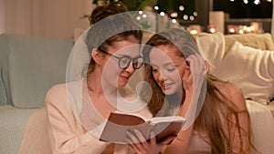 Happy female friends reading book at home