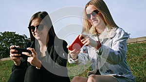 Happy female friends with smartphones playing mobile game, summer vacation