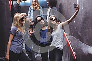 Happy female friends taking selfie while standing on steps