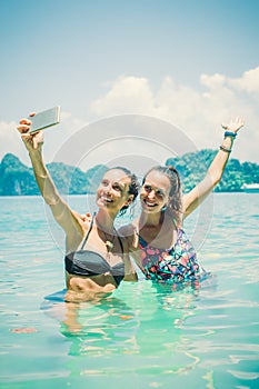 Happy female friends on vacation taking selfie photograph in wat