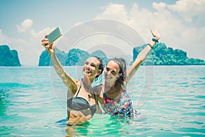 Happy female friends on vacation taking selfie photograph in wat